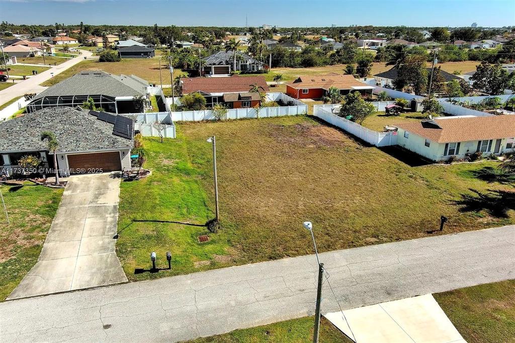 An aerial view shows a vacant residential lot situated between two existing houses — 2013 NE 18TH AVENUE, CAPE CORAL, FL