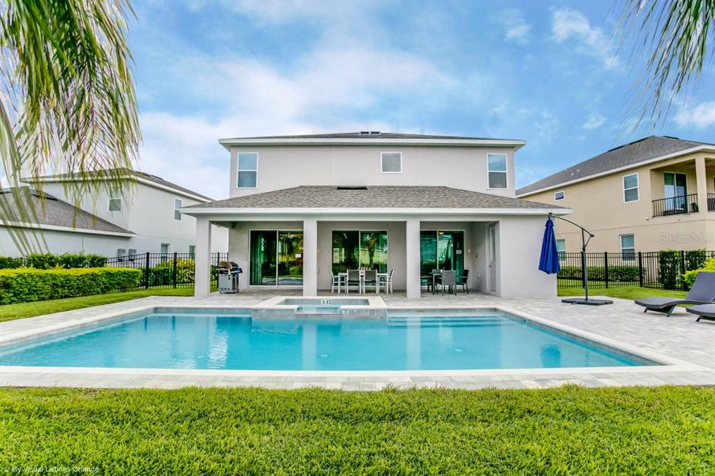 A two-story house exterior features a covered patio, a swimming pool, and a fenced yard — 7736 GRABEN STREET, KISSIMMEE, FL