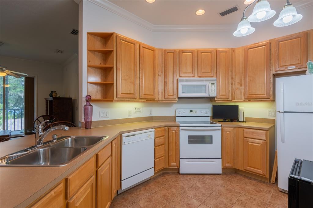 A kitchen with wood cabinets, white appliances, and a double sink on a laminate countertop — 6815 DALI AVENUE UNIT 205, LAND O LAKES, FL