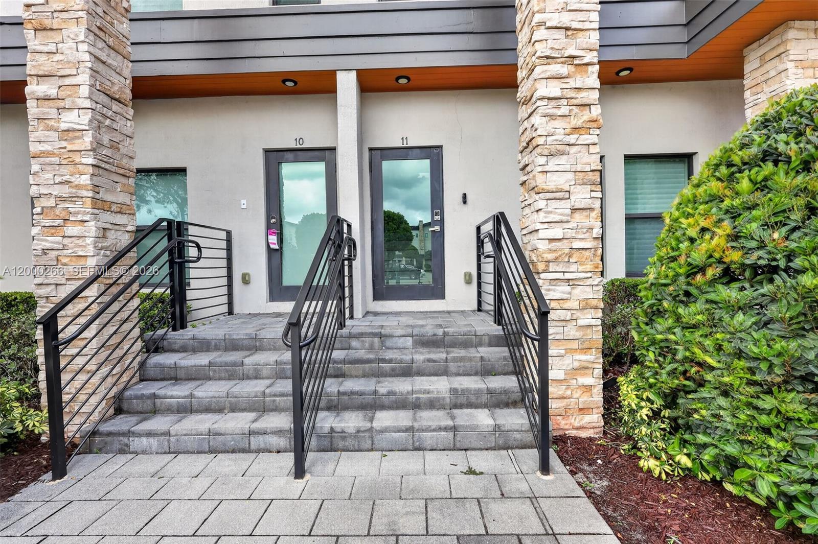 The exterior view shows two adjacent building entrances with stone pillars and metal railings — 10467 NW 82nd St # 11, Doral FL 33178, DORAL, FL