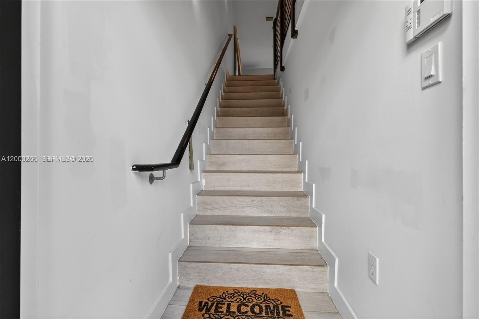 A straight wooden staircase with a black handrail leads upward between two white walls — 10467 NW 82nd St # 11, Doral FL 33178, DORAL, FL