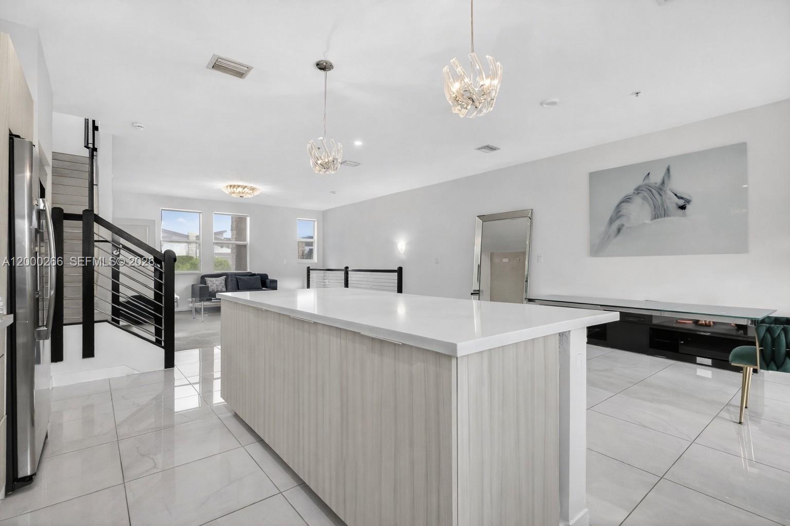 A modern kitchen island with a white countertop sits in an open-concept living space — 10467 NW 82nd St # 11, Doral FL 33178, DORAL, FL