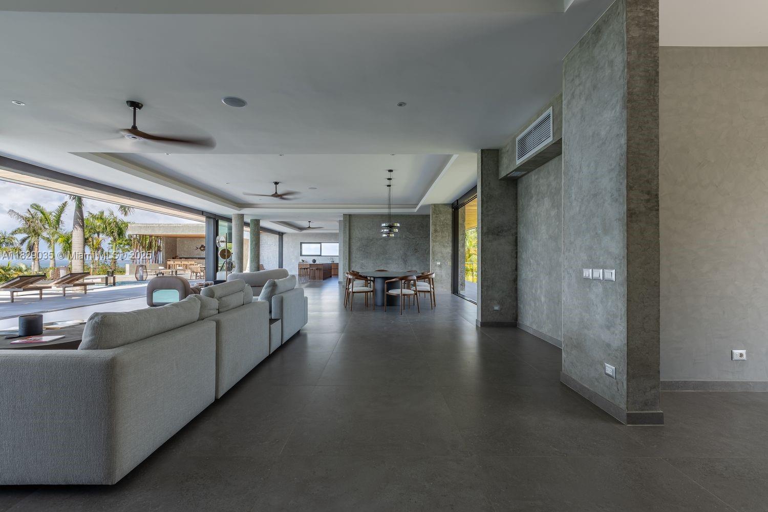 A spacious open-plan living and dining area features concrete-style walls, tile flooring, and sliding doors — 000 8G99+hr Las Terrenas, Dominican Republic, FL 32000, FL
