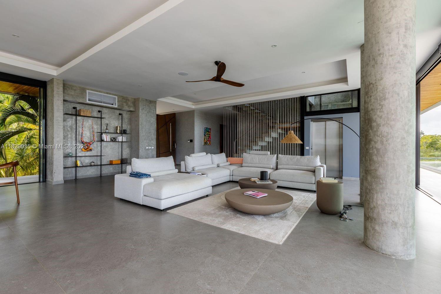 A modern living room features a large sectional sofa, concrete columns, and floor-to-ceiling glass doors — 000 8G99+hr Las Terrenas, Dominican Republic, FL 32000, FL