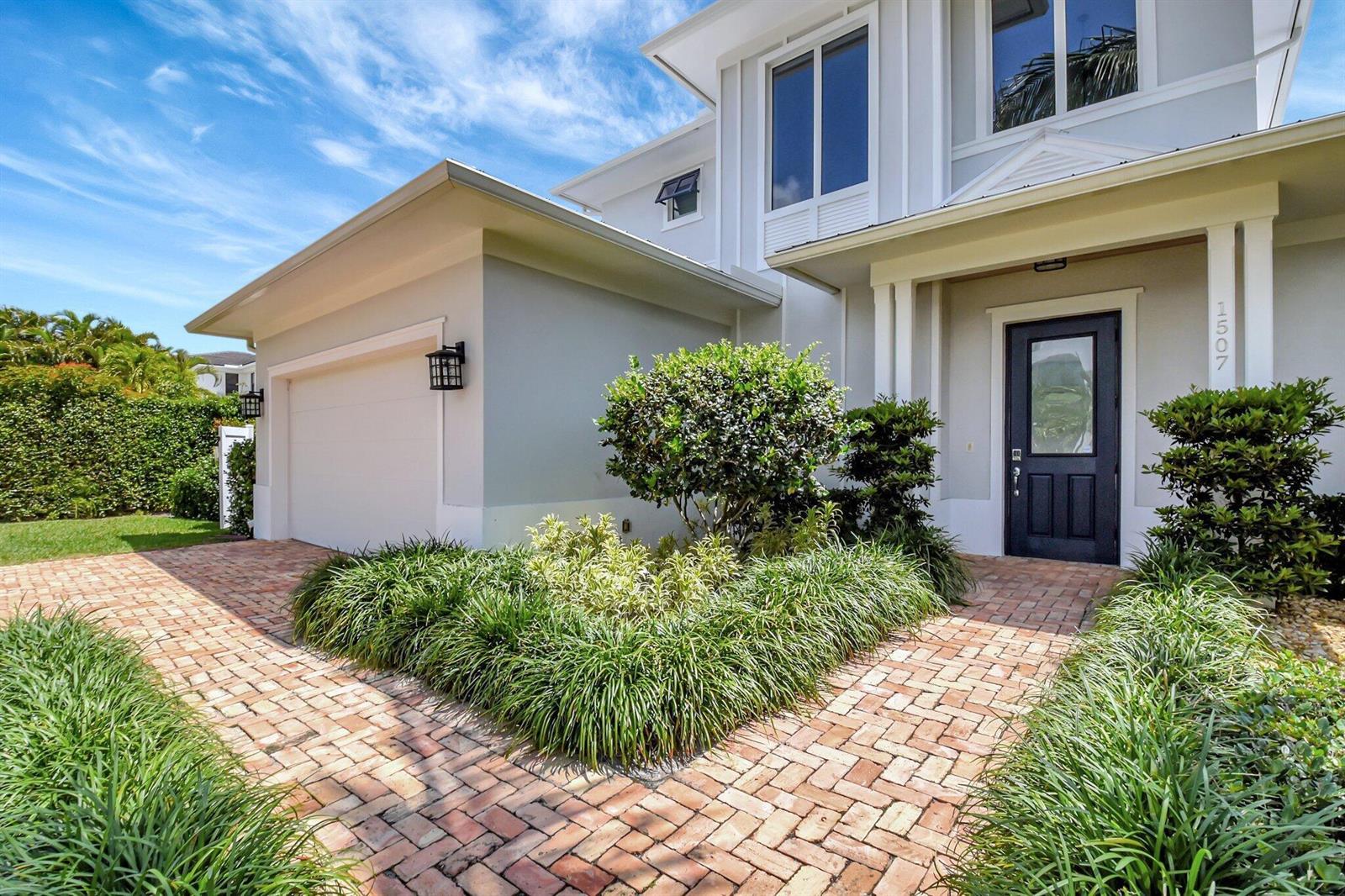 A two-story house exterior features a brick walkway, a garage, and a dark front door — 1507 Pine Lane, Delray Beach FL 33444, DELRAY BEACH, FL