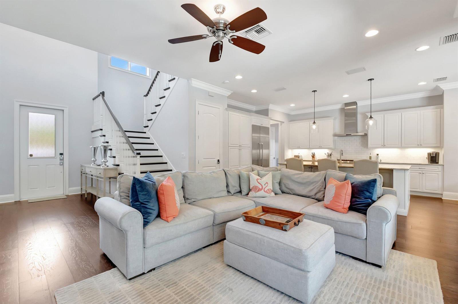 A living room with a sectional sofa, ottoman, and staircase opens to a white kitchen — 1507 Pine Lane, Delray Beach FL 33444, DELRAY BEACH, FL