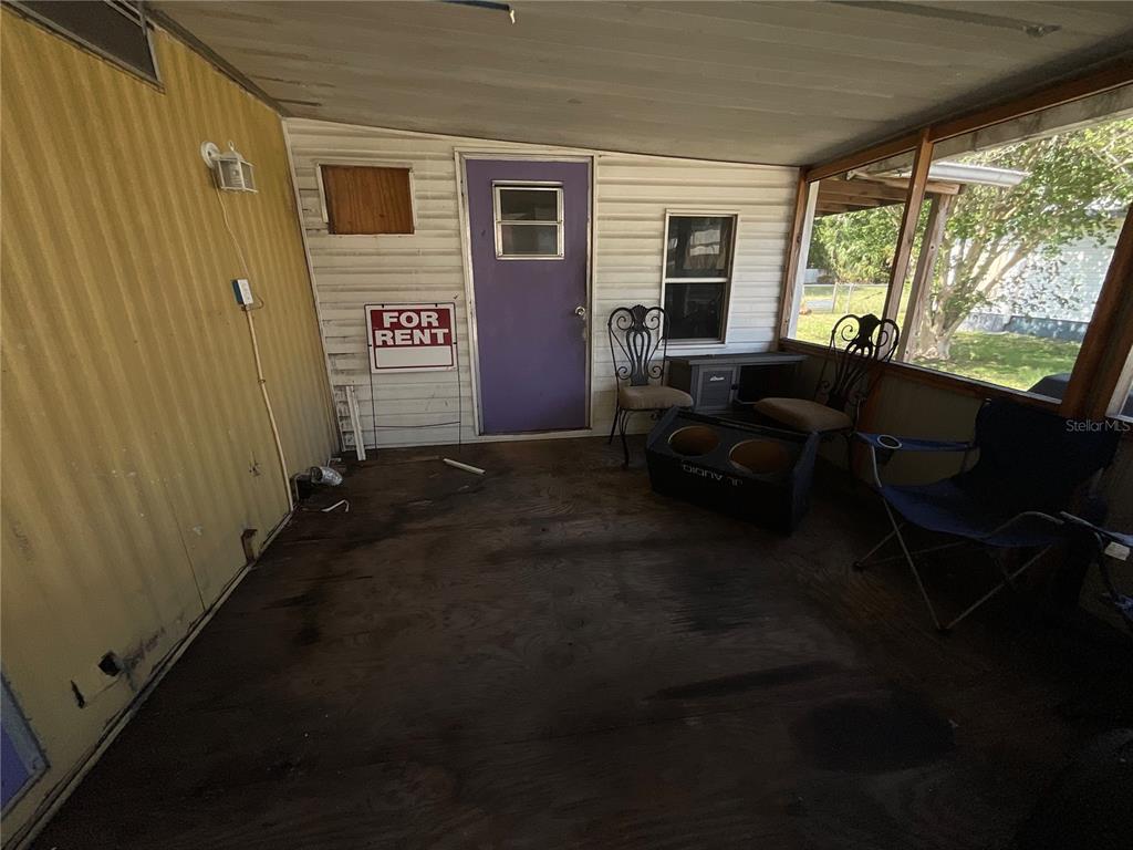 A covered porch with a purple door, a for rent sign, and worn wooden flooring — 702 JERSEY COURT, DUNDEE, FL