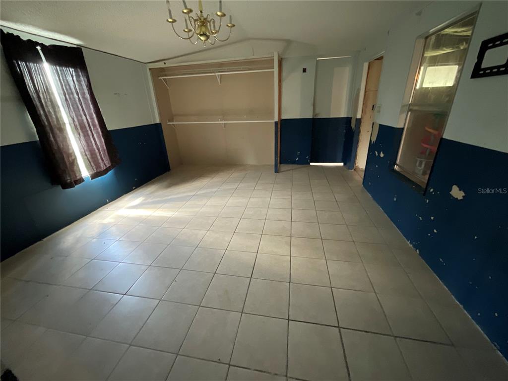 A room with tiled flooring, blue and white walls, and an open closet area — 702 JERSEY COURT, DUNDEE, FL