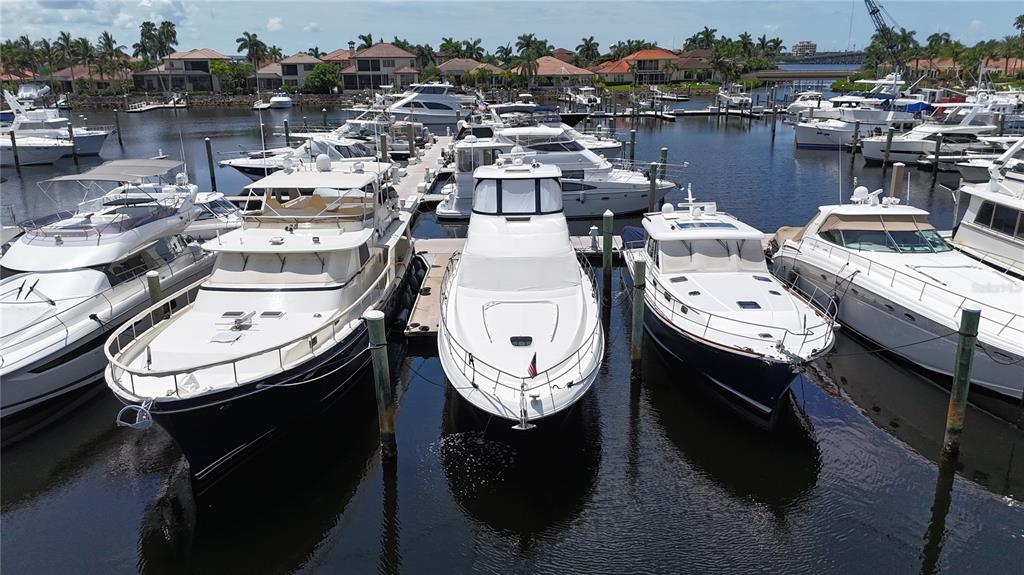 A high-angle view shows several yachts docked in a marina lined with waterfront houses — 102 RIVIERA DUNES WAY UNIT S-11, PALMETTO, FL
