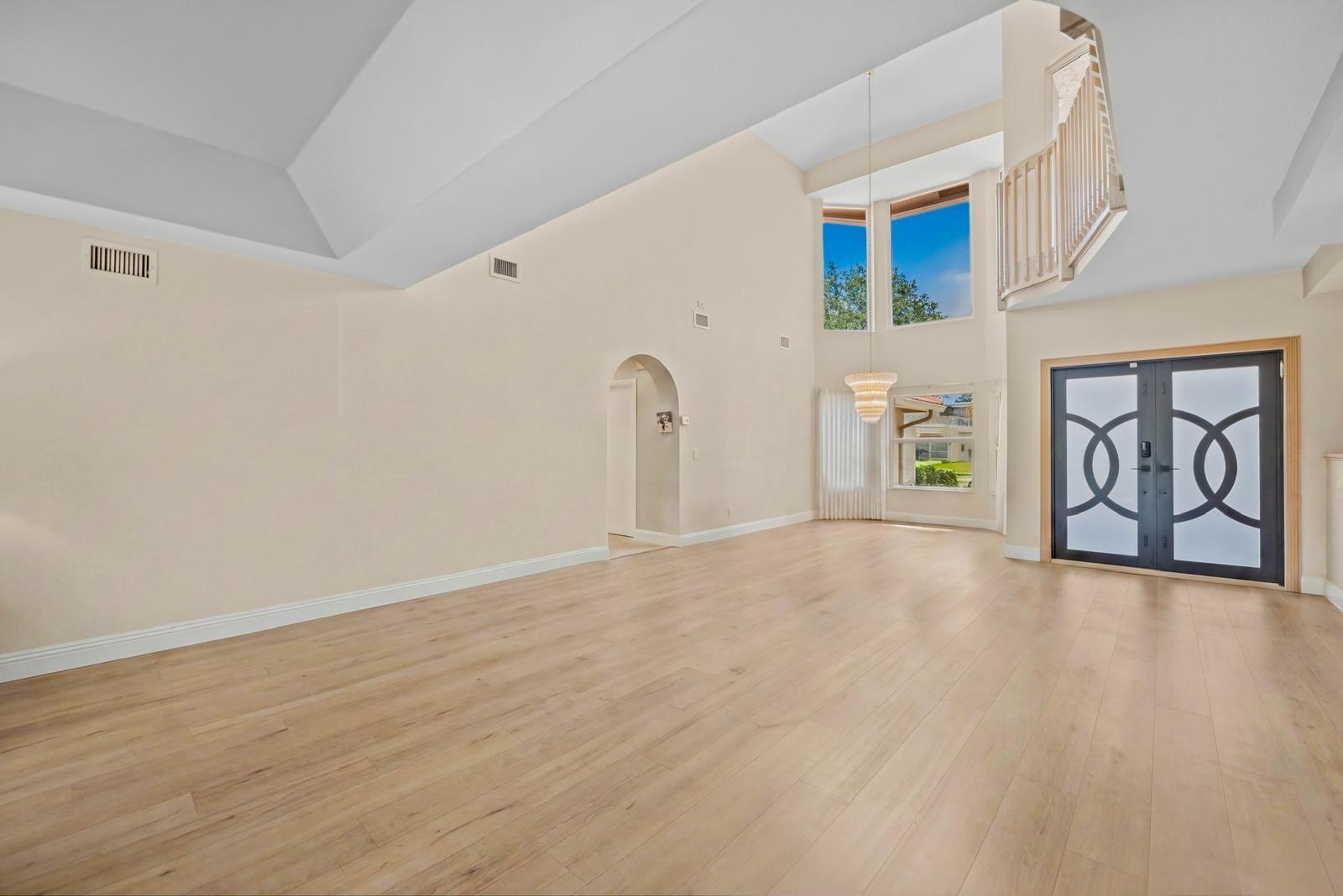 A spacious living room features high vaulted ceilings, light wood flooring, and a grand staircase — 9410 Sea Turtle Manor, Plantation FL 33324, PLANTATION, FL