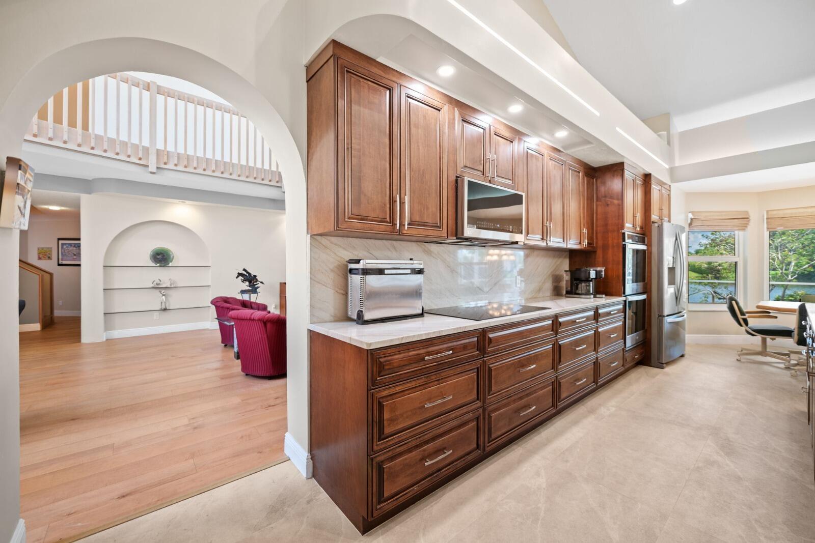 A kitchen with dark wood cabinetry, stainless steel appliances, and a marble backsplash — 9410 Sea Turtle Manor, Plantation FL 33324, PLANTATION, FL