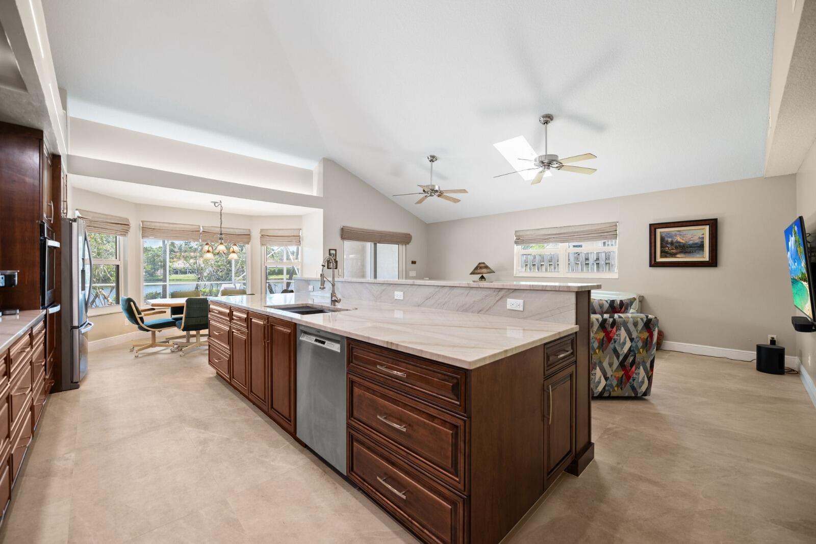 A kitchen with dark wood cabinets, a large stone island, and a view of water — 9410 Sea Turtle Manor, Plantation FL 33324, PLANTATION, FL