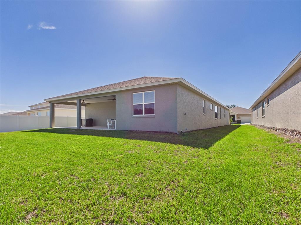 The exterior of a single-story house features a covered patio and a grassy backyard — 7813 SW 56TH PLACE, OCALA, FL