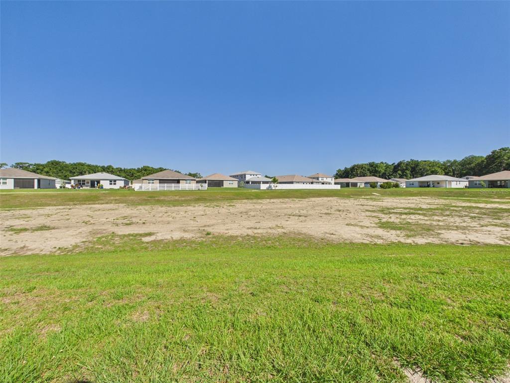 A large, vacant grassy lot sits in front of a row of suburban houses — 7813 SW 56TH PLACE, OCALA, FL