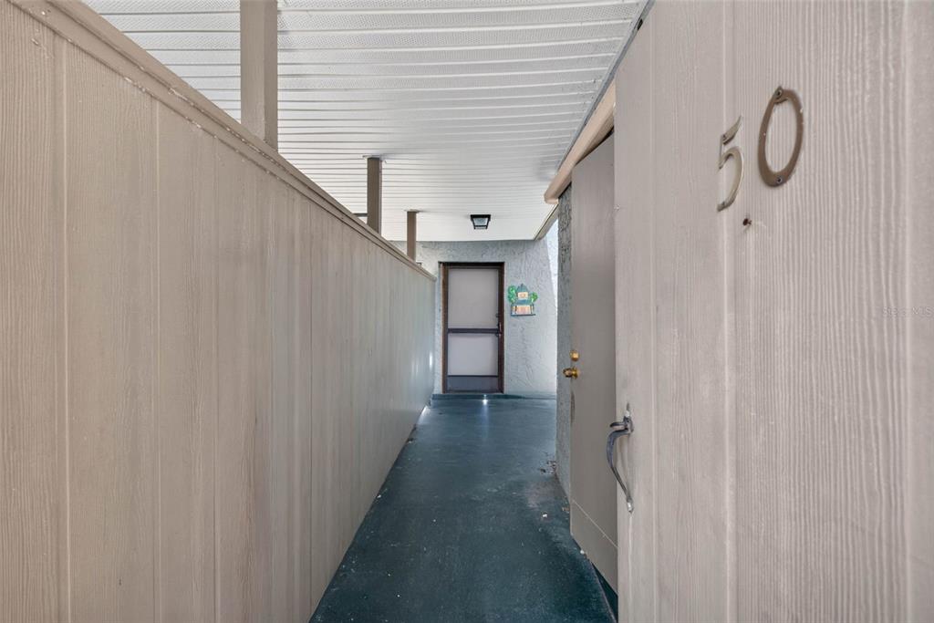 A covered walkway leads to a front door with a screen door and number 50 — 2500 21ST STREET NW UNIT 50, WINTER HAVEN, FL