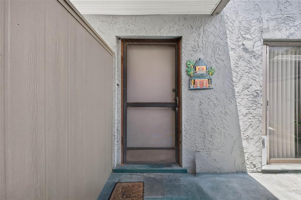 A screen door with a decorative wall hanging sits at the entrance of a home — 2500 21ST STREET NW UNIT 50, WINTER HAVEN, FL