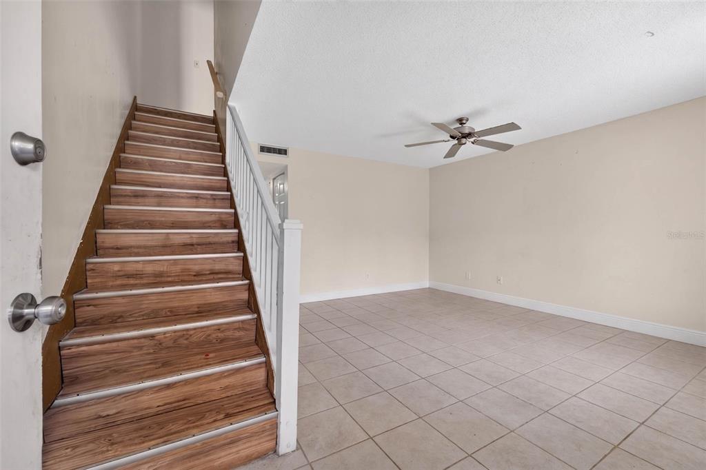 A room with tiled flooring and a wooden staircase leading to an upper level — 2500 21ST STREET NW UNIT 50, WINTER HAVEN, FL
