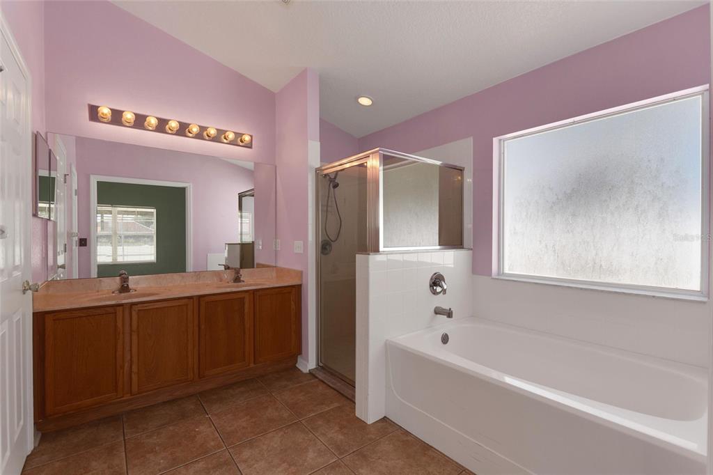 A bathroom features a double vanity, a glass-enclosed shower, and a white soaking tub — 844 BERWICK DR, DAVENPORT, FL