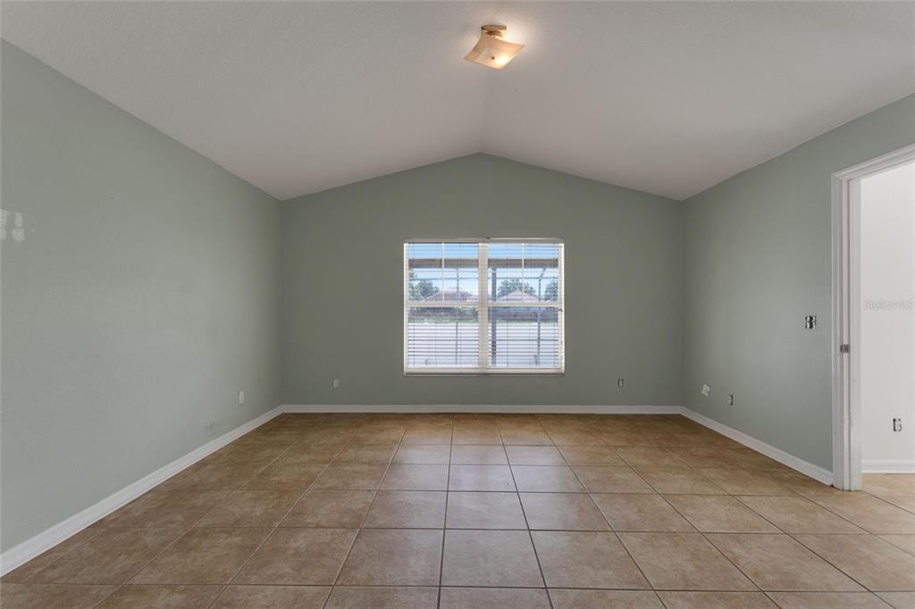 An empty room with light green walls, tan tile flooring, and a vaulted ceiling — 844 BERWICK DR, DAVENPORT, FL