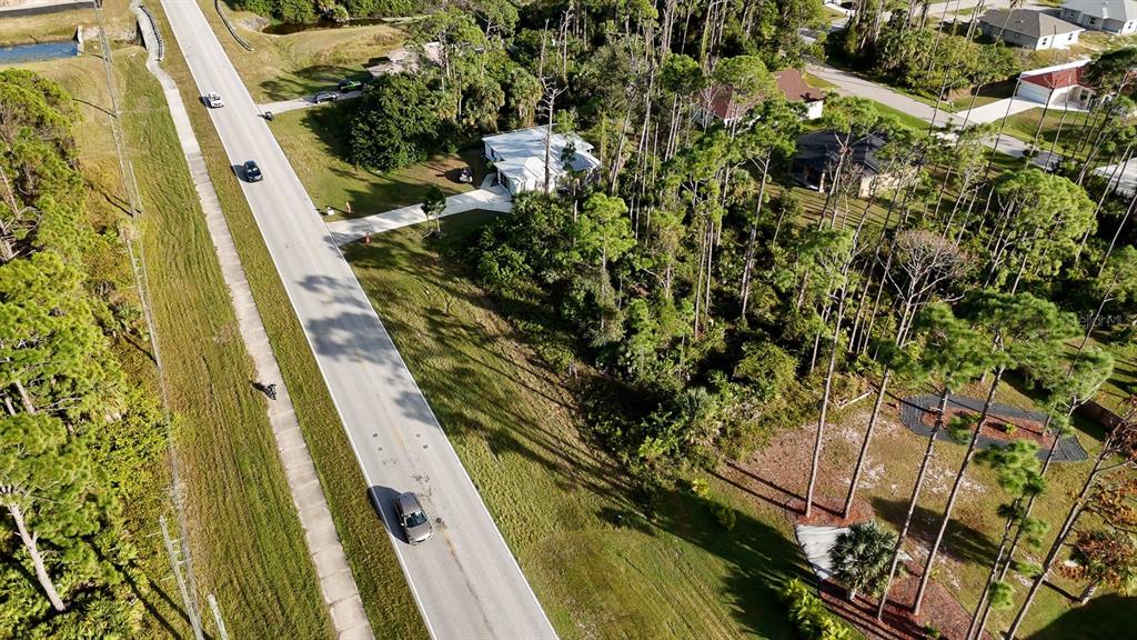 An aerial view shows a road, a house with a driveway, and surrounding wooded areas — E PRICE BOULEVARD, NORTH PORT, FL
