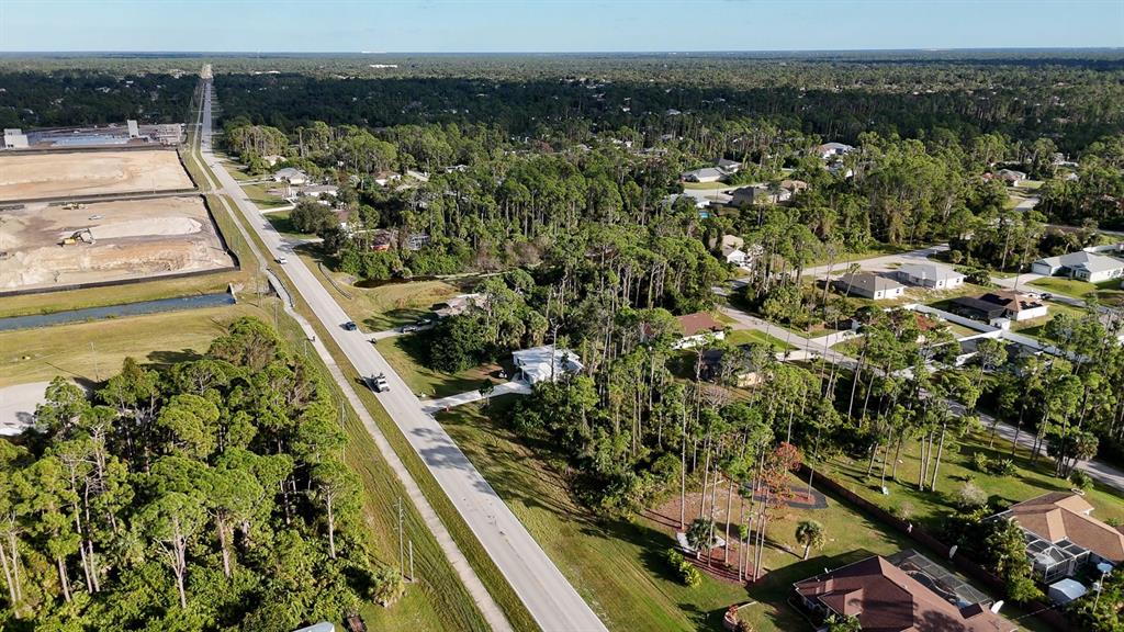 An aerial view shows a residential neighborhood with houses, dense trees, and a construction site — E PRICE BOULEVARD, NORTH PORT, FL