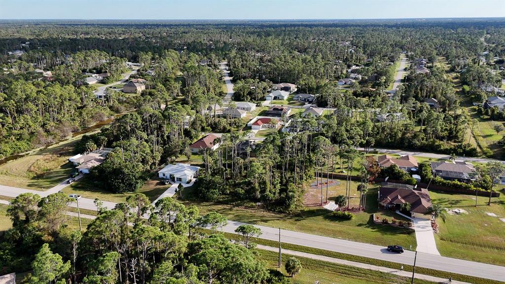 An aerial view shows a suburban neighborhood with houses surrounded by dense pine trees — E PRICE BOULEVARD, NORTH PORT, FL