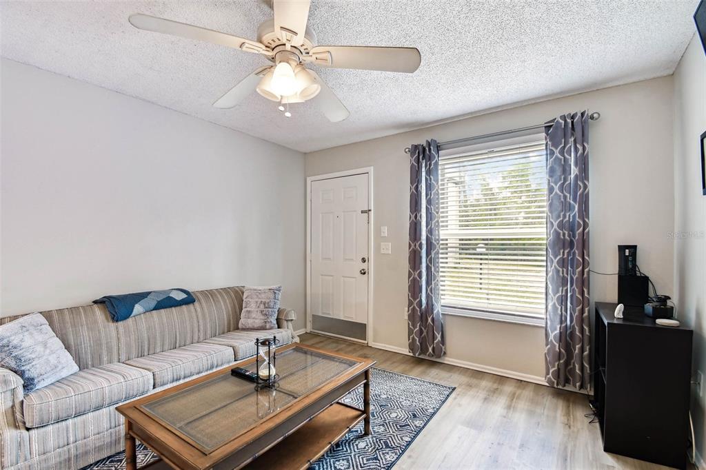 A living room features a striped sofa, a glass-top coffee table, and a ceiling fan — 3718 59TH AVE W UNIT 3718, BRADENTON, FL