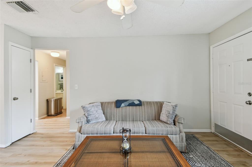 A living room features a striped sofa, a glass-topped coffee table, and light wood flooring — 3718 59TH AVE W UNIT 3718, BRADENTON, FL
