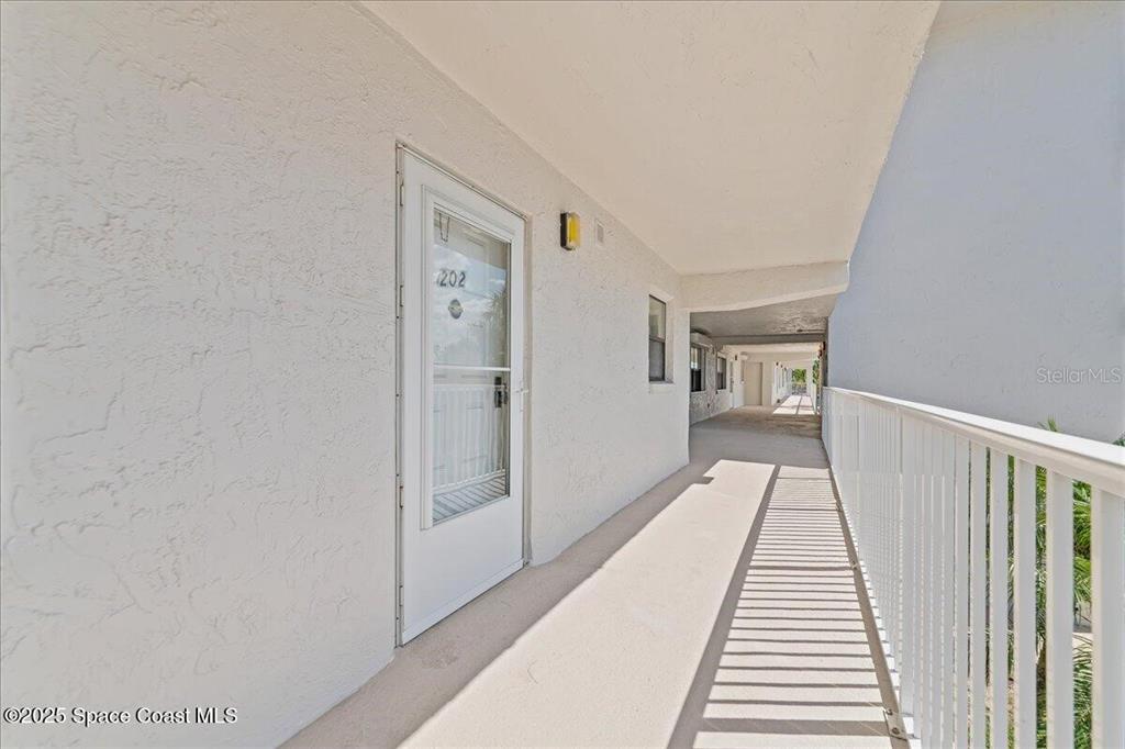An exterior walkway leads to a white door marked 202 at a multi-story building — 2160 N HIGHWAY A1A UNIT 202, INDIALANTIC, FL