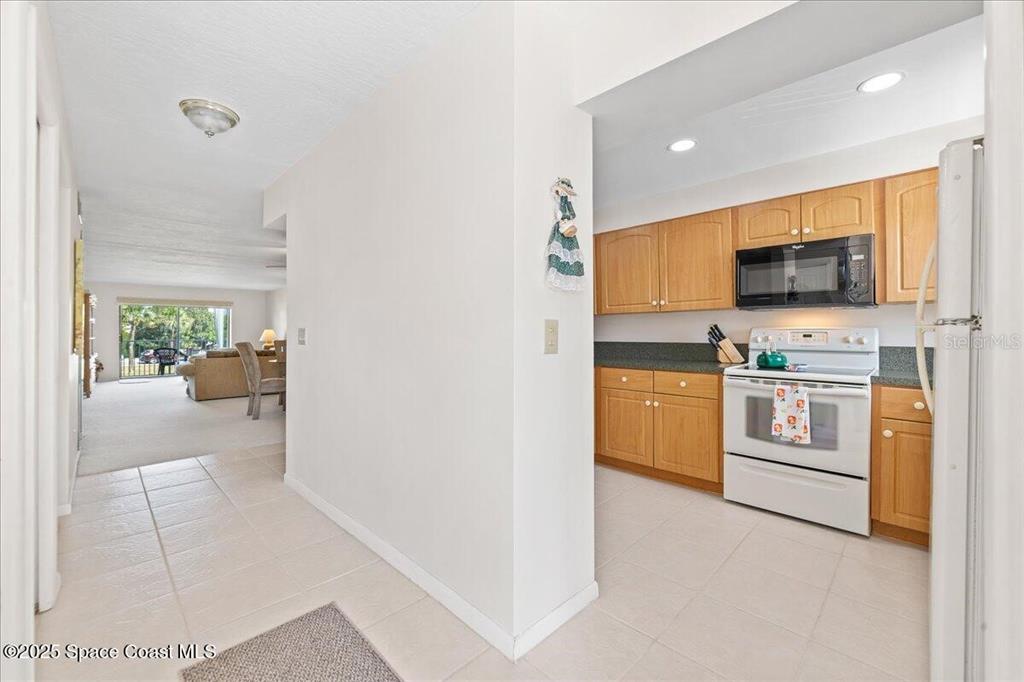 A tiled entryway leads to a kitchen with light wood cabinets and a living area — 2160 N HIGHWAY A1A UNIT 202, INDIALANTIC, FL