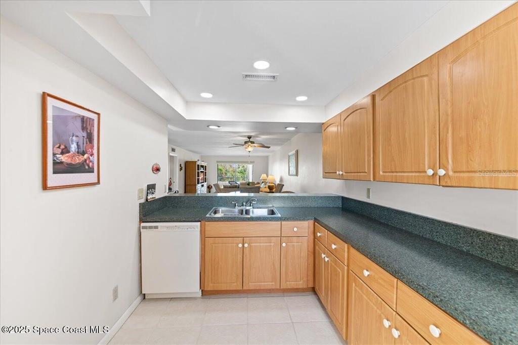 A kitchen features light wood cabinets, dark countertops, and a view into the living area — 2160 N HIGHWAY A1A UNIT 202, INDIALANTIC, FL