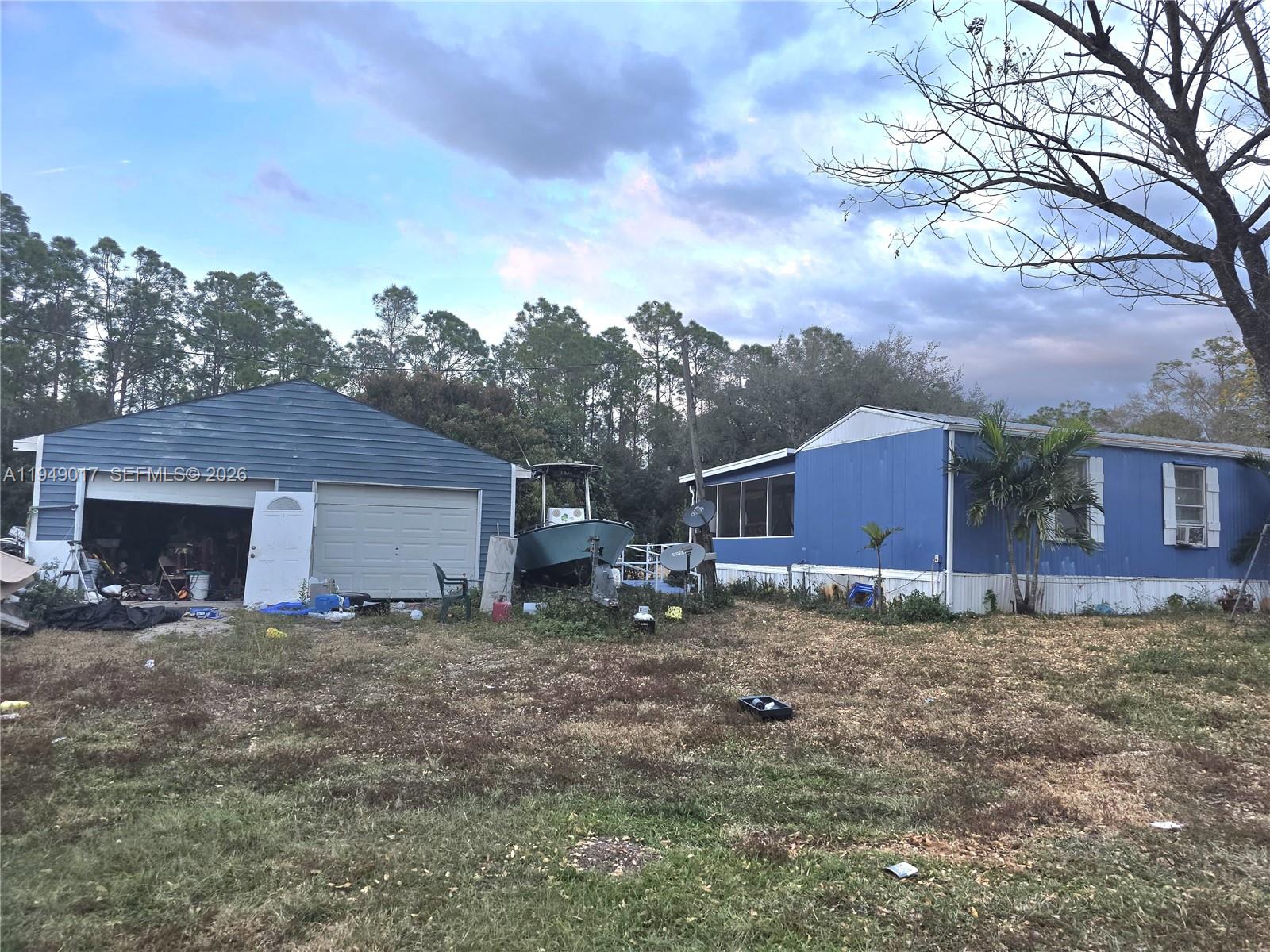 A blue detached garage and a blue mobile home sit on a grassy lot — 575 VERO AVE, Clewiston FL 33440, CLEWISTON, FL