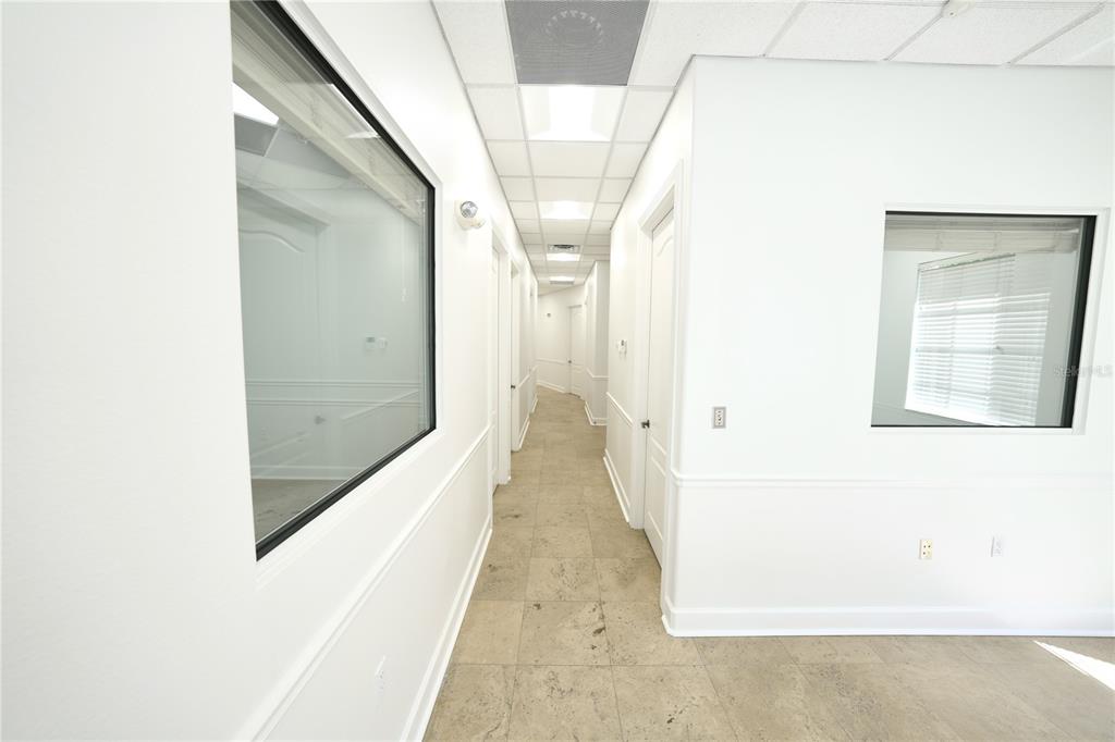 A long, white-walled office hallway features tile flooring, drop ceilings, and several interior windows — 2009 LONGWOOD LAKE MARY ROAD, LONGWOOD, FL