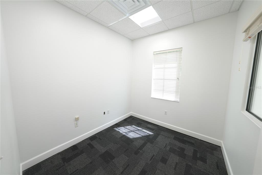 An empty office with white walls, a window with blinds, and dark patterned carpet — 2009 LONGWOOD LAKE MARY ROAD, LONGWOOD, FL