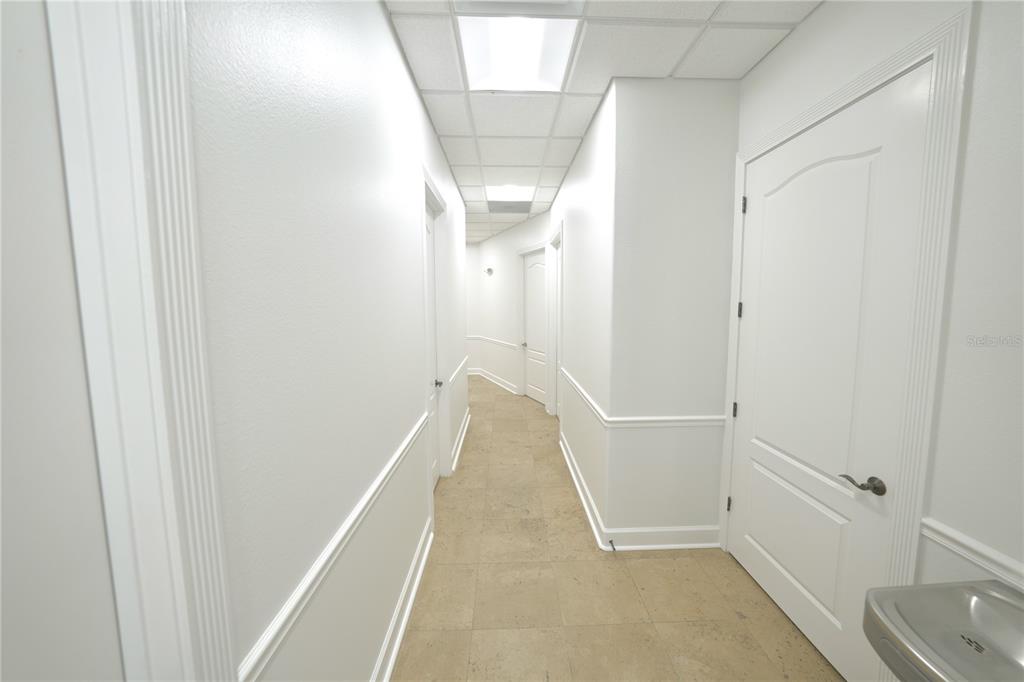 A bright hallway with white walls, wainscoting, tile flooring, and several closed white doors — 2009 LONGWOOD LAKE MARY ROAD, LONGWOOD, FL