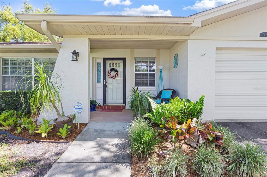 The exterior of a single-story home features a covered entryway, a front door, and landscaping — 2220 MARSHALL DRIVE, DUNEDIN, FL