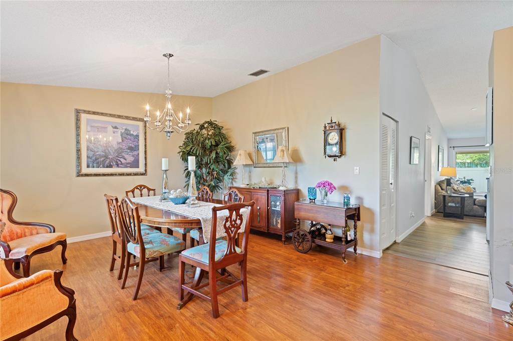 A dining room features a wooden table with chairs, a chandelier, and hardwood flooring — 2220 MARSHALL DRIVE, DUNEDIN, FL