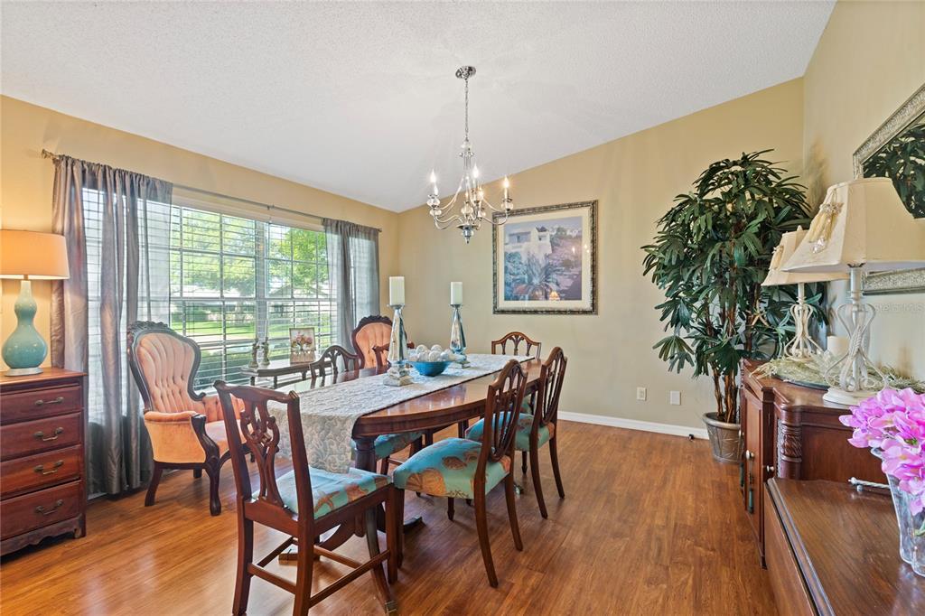 A dining room features a wooden table, chairs with blue cushions, and a chandelier — 2220 MARSHALL DRIVE, DUNEDIN, FL