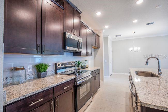 A kitchen features dark wood cabinets, granite countertops, stainless steel appliances, and a center island — TBD SW 128TH PLACE, OCALA, FL