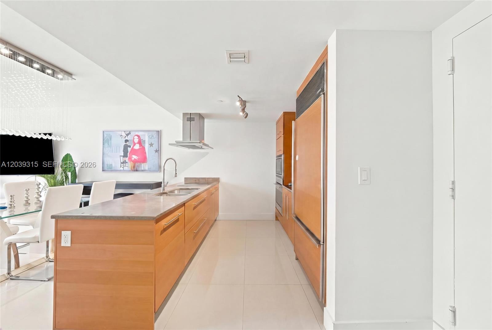 A modern kitchen features wood cabinetry, a long island, and stainless steel appliances — 485 Brickell Ave # 3707, Miami FL 33131, MIAMI, FL