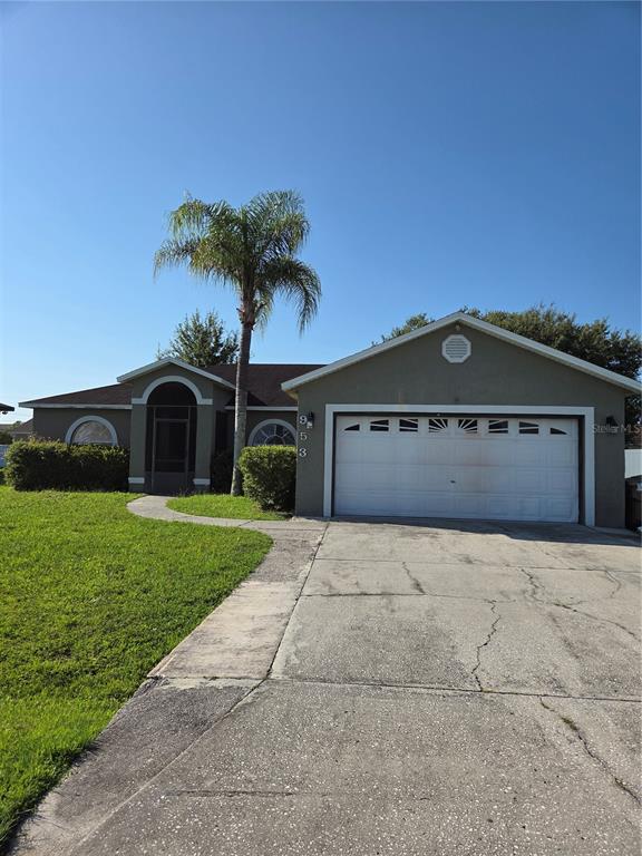 A single-story house with a two-car garage, a palm tree, and a concrete driveway — 953 LOUVRE COURT, KISSIMMEE, FL