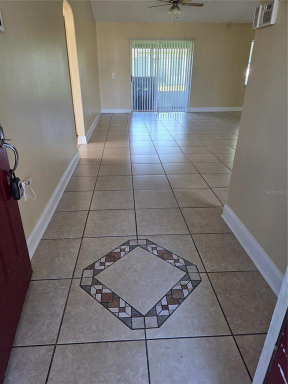 An entryway with a decorative tile medallion leads into a living area with sliding doors — 953 LOUVRE COURT, KISSIMMEE, FL