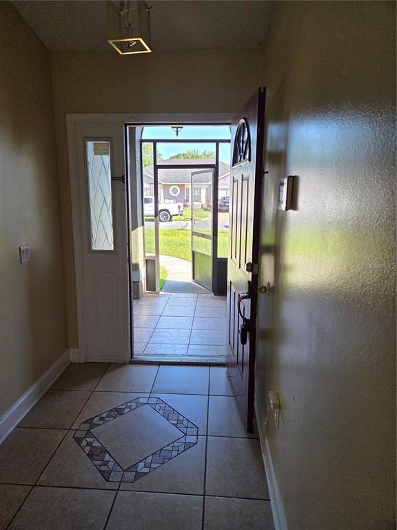 An entryway with tiled floors leads to an open front door and a screened porch — 953 LOUVRE COURT, KISSIMMEE, FL