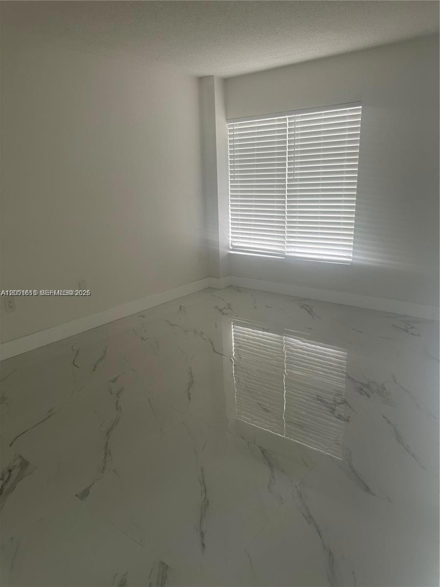 An empty room features white walls, white baseboards, and polished white marble-patterned tile flooring — 4166 Inverrary Dr # 210, Lauderhill FL 33319, LAUDERHILL, FL
