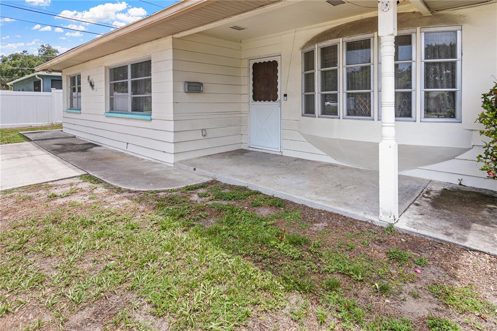 The exterior of a single-story house features a concrete porch, white siding, and a bay window — 5331 98TH WAY N, ST PETERSBURG, FL