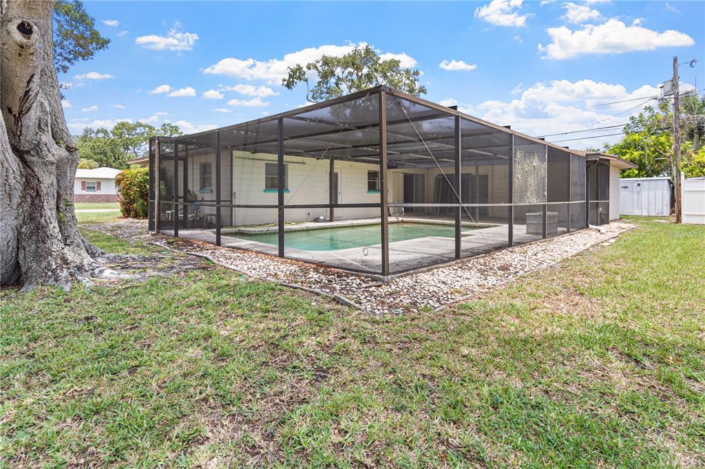 A backyard features a screened-in swimming pool attached to the rear of a single-story house — 5331 98TH WAY N, ST PETERSBURG, FL