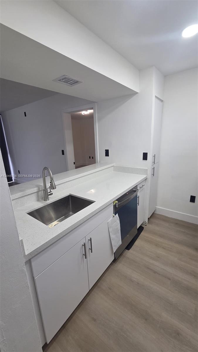 A kitchen features white cabinets, a stainless steel sink, a dishwasher, and light-colored countertops — 7125 NW 186th St # B201, Hialeah FL 33015, HIALEAH, FL