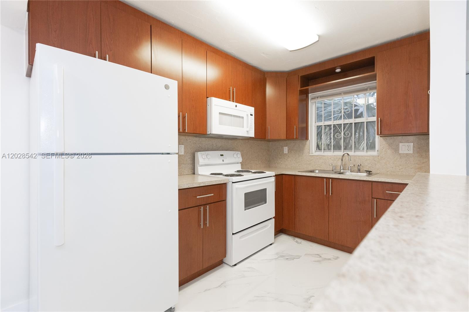 A kitchen features wood cabinets, white appliances, a window, and light-colored countertops and flooring — 1060 NE 78th St Rd # 3, Miami FL 33138, MIAMI, FL