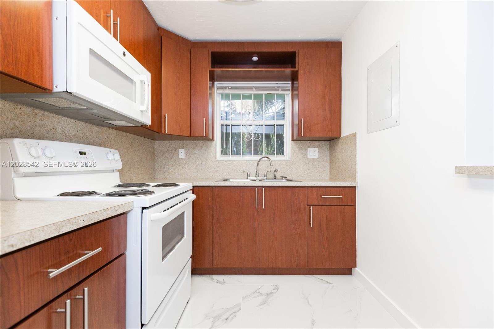 A kitchen features wood cabinets, white appliances, a window above the sink, and marble flooring — 1060 NE 78th St Rd # 3, Miami FL 33138, MIAMI, FL