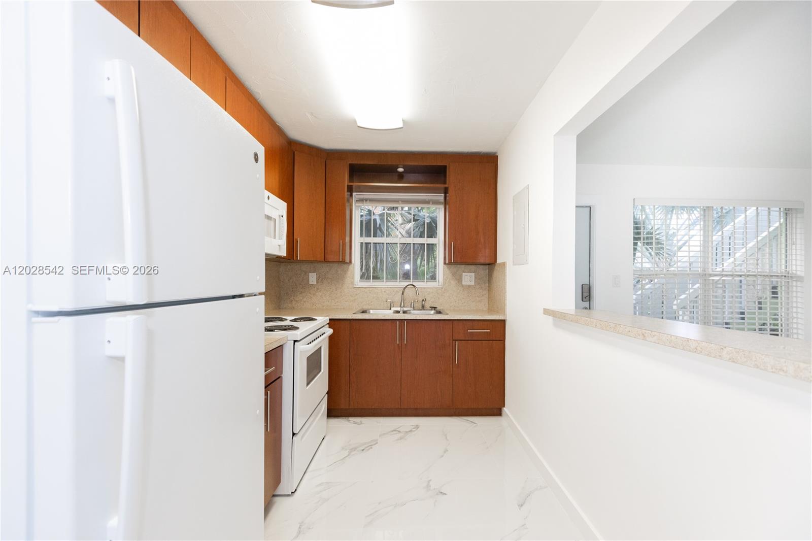 A kitchen features wood cabinets, white appliances, and white marble-patterned tile flooring — 1060 NE 78th St Rd # 3, Miami FL 33138, MIAMI, FL